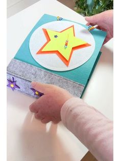 a child's hand is pointing at a paper star on a piece of fabric