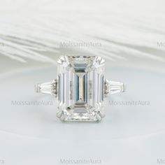 an emerald - cut diamond ring with baguets and side stones, mounted on a white background