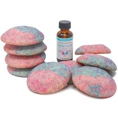 a pile of pink and blue cookies next to a bottle of liquid