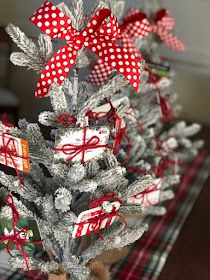 a small christmas tree with red and white bows on it's branches, wrapped in gift tags