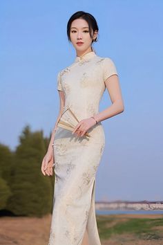 A beautiful woman in a long white qipao Chinese dress with short sleeves Elegant White Cheongsam For Spring, White Fitted Cheongsam With Stand Collar, Elegant Beige Dress With Stand Collar, Elegant Ao Dai With Stand Collar For Spring, Elegant Spring Ao Dai With Stand Collar, Elegant Spring Cheongsam With Stand Collar, Spring Elegant Cheongsam With Stand Collar, Elegant Fitted Midi Dress With Stand Collar, White Fitted Cheongsam For Party