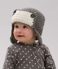 a small child wearing a gray and white knitted hat with polka dots on it