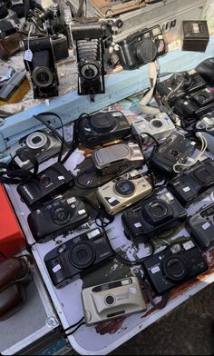 there are many cameras on display at the market table, including one that is full of them