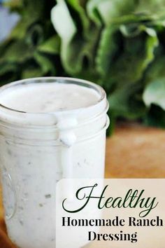 a jar filled with homemade ranch dressing sitting on top of a wooden cutting board next to a green plant