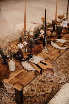 a wooden table topped with plates and candles