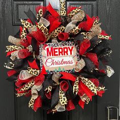 a christmas wreath with leopard print, red and black ribbon on the front door to a house