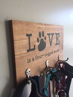 a wooden sign that says love is a four legged word with dog paw prints on it