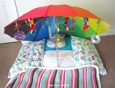 an umbrella is sitting on top of a bed with pillows and blankets underneath it,