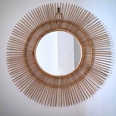 a mirror that is made out of bamboo sticks and has a circular frame around it