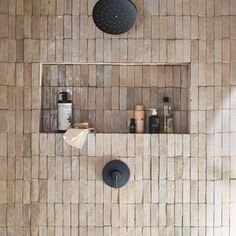 a tiled shower with two black faucets and soap dispensers on the wall