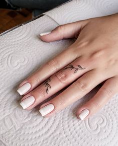 a woman's hand with a small flower tattoo on her left thumb and finger