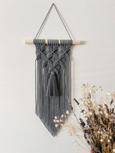 the wall hanging is decorated with black and white tassels, along with dried flowers