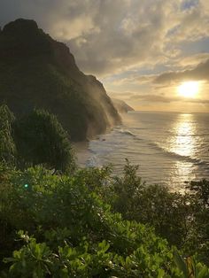 the sun is setting over the ocean and mountains