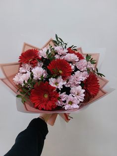 a person holding a bouquet of red and pink flowers