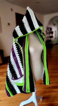 a white mannequin wearing a black and green striped scarf