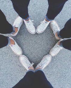 four people standing in a circle wearing white tennis shoes