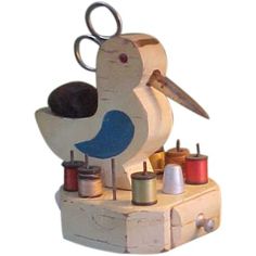 a wooden bird with scissors and thread spools