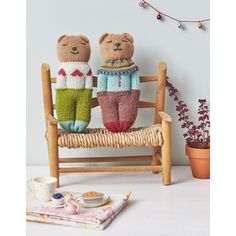 two knitted teddy bears sitting on a wooden bench