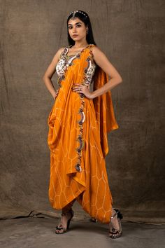 Mango pre-draped dhoti saree with bandhani print and embroidery on the drape. Comes with white embroidered blouse.
Component: 2
Pattern: Embroidery and Print
Type Of Work: Zardozi, Coin, Sequin and Bandhani
Neckline: V neck
Sleeve Type: Sleeveless
Fabric: Crepe
Color: Orange,White
Other Details: 
Scalloped detail at the neckline
Semi elasticated waistband
Occasion: Wedding - Aza Fashions Designer Draped Saree For Navratri, Navratri Pre-draped Saree With Cutdana, Bollywood Style Pre-draped Saree With Side Open Dupatta, Designer Pre-draped Saree With Traditional Drape, Designer Draped Dress With Zari Work, Draped Cutdana Sets For Designer Wear, Designer Wear Pre-draped Saree For Diwali, Bollywood Style Draped Art Silk Sets, Bollywood Draped Art Silk Sets