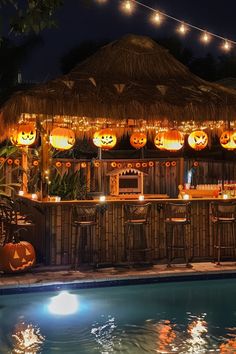 an outdoor bar decorated for halloween with pumpkins on the roof and lights hanging over it