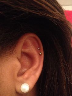 a woman's ear with a single pearl in the middle and two small pearls on each side