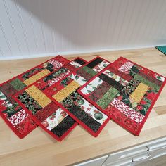 four quilted placemats sitting on top of a wooden floor next to a stove