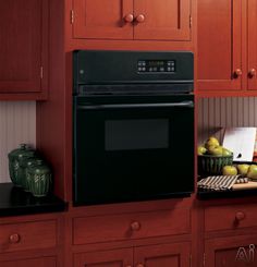 a black microwave oven sitting on top of a kitchen counter next to wooden cupboards