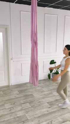 a woman in white shirt and beige pants standing next to a pink umbrella hanging from the ceiling