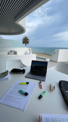 an open laptop computer sitting on top of a white table next to a notebook and pen