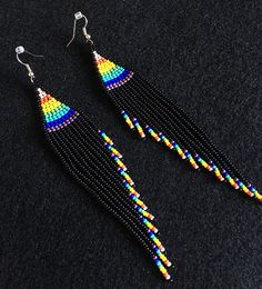 a pair of multicolored beaded earrings on a black surface with silver earwires