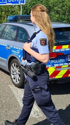 a woman police officer walking in front of a car