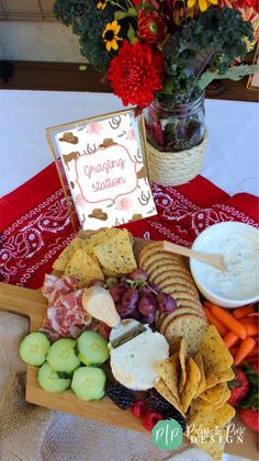 a platter with crackers, fruit and vegetables on it next to a greeting card