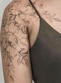 a woman's arm with flowers and leaves tattooed on the back of her shoulder