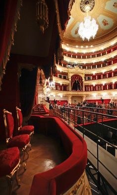 an auditorium filled with red seats and chandeliers