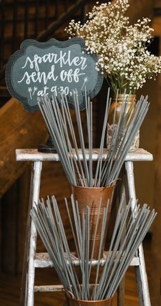 a vase filled with white flowers sitting on top of a wooden chair next to a chalkboard