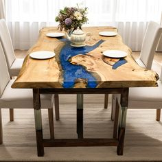 a wooden table with white chairs and plates on it