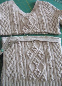 two knitted sweaters sitting on top of a cutting board