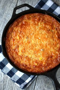 a skillet filled with food sitting on top of a checkered table cloth next to a knife and fork