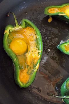 some green peppers are cooking in a skillet with an egg yolk on top