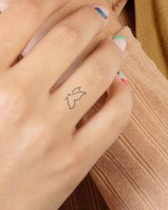 a close up of a person's hand with a tattoo on their ring finger