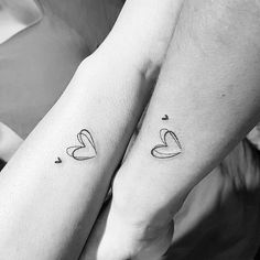 two people holding hands with tattoos on their arms