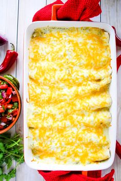 a casserole dish with cheese and vegetables on the side next to a bowl of salsa