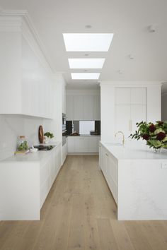 a kitchen with white cabinets and wood flooring is seen in this image from the hallway