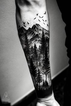 a man's arm with trees and birds on it