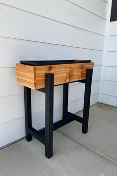 a wooden table sitting on the side of a house