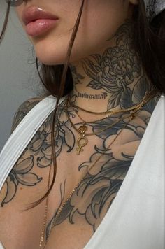 a woman with tattoos on her chest wearing a white top and black glasses is looking at the camera