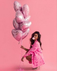 a woman in a pink dress holding balloons