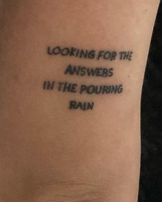 a tattoo with the words looking for the answers in the pouring rain written on it