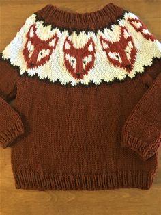 a brown sweater with white and red designs on it