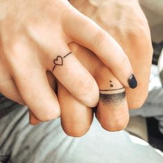 two people holding hands with tattoos on their fingers